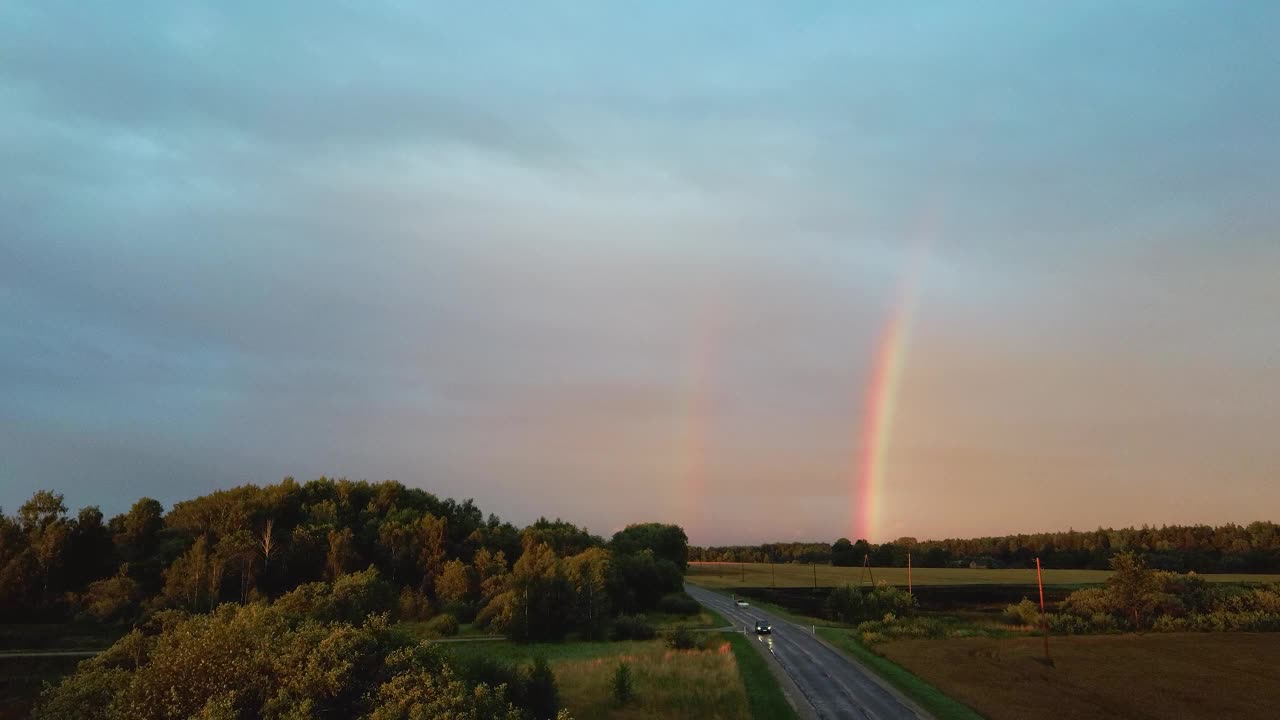 森林和麦田上的双彩虹。乡村公路上的黑色雷雨云和彩虹景观。区域Dron开枪。视频素材