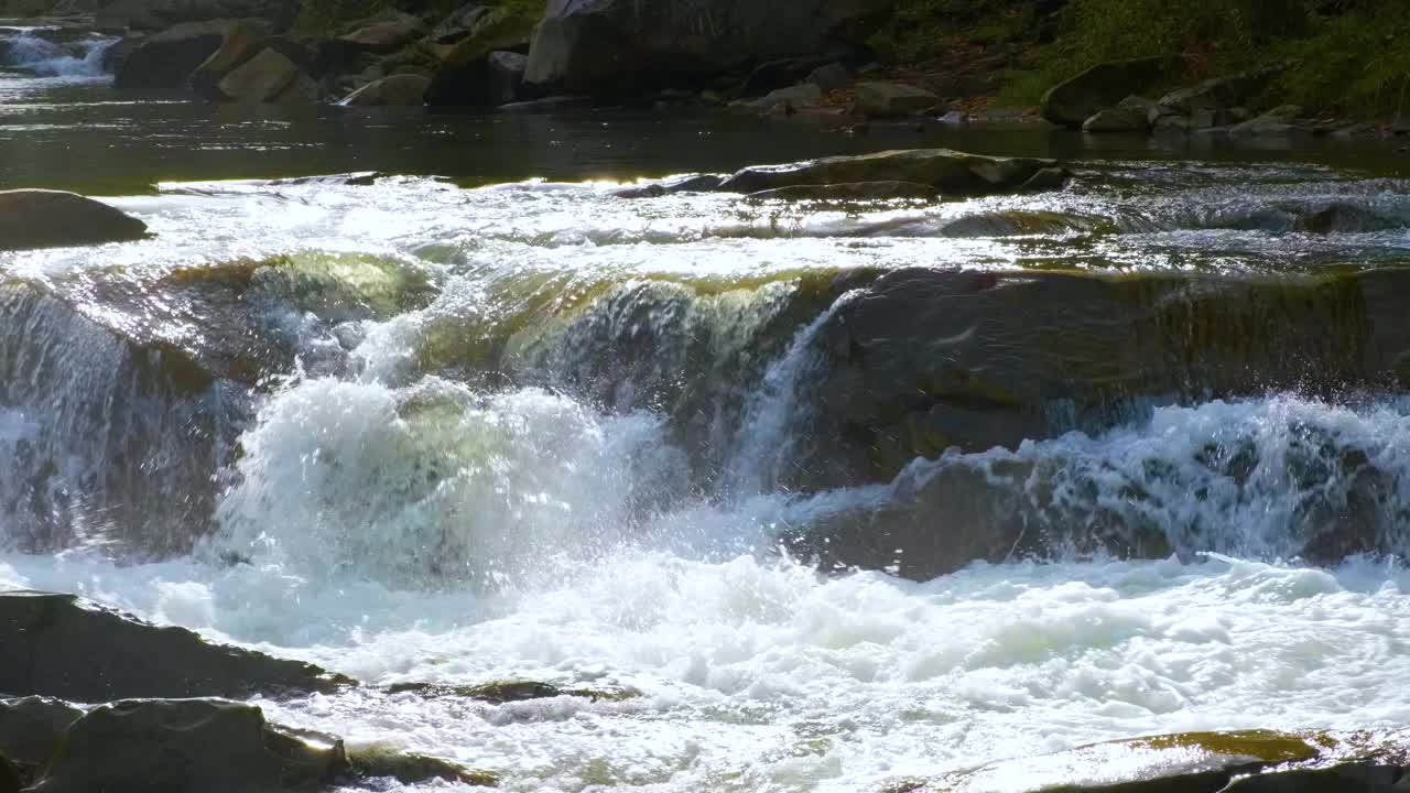 山河，清澈的绿松石水瀑布落在潮湿的卵石与厚厚的白色泡沫。视频素材