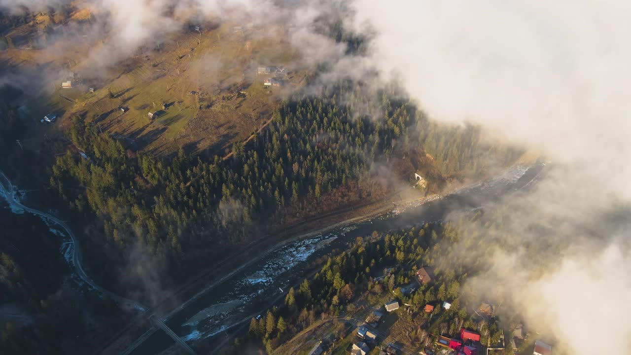 鸟瞰充满活力的景观，雾蒙蒙的云朵覆盖着小山和散落的小村舍。视频素材