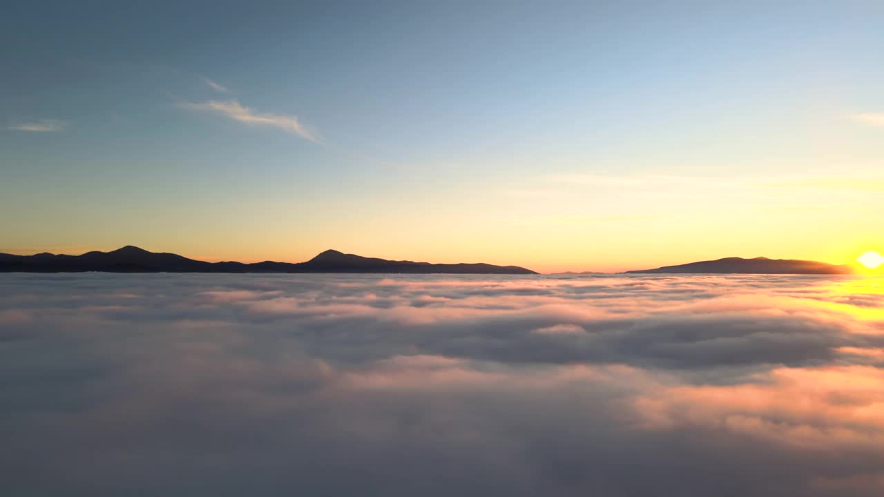 鸟瞰图生机勃勃的黄色日出在白色浓密的云和遥远的山脉在地平线上。视频素材