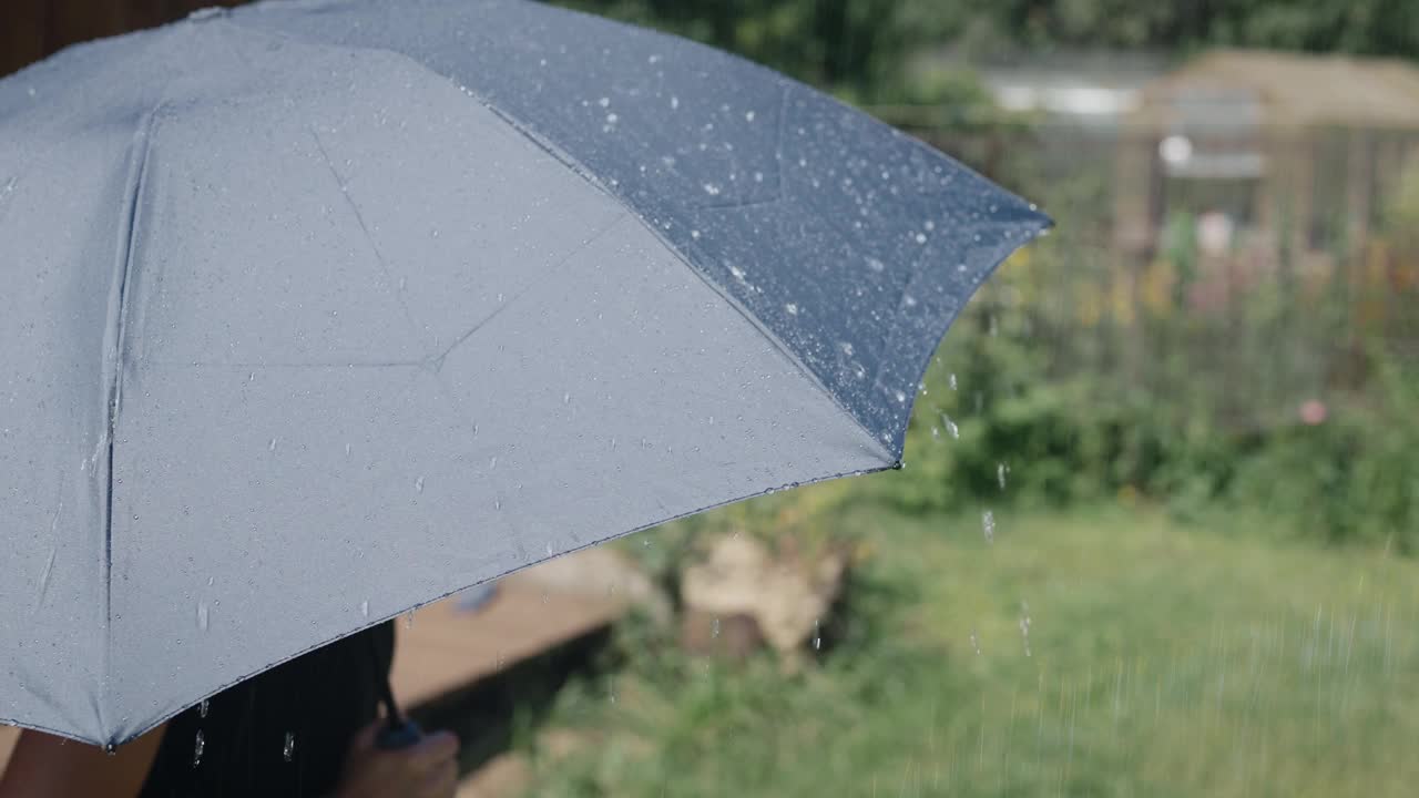 阳光明媚的夏雨。水珠从灰色的伞面上流下来视频素材