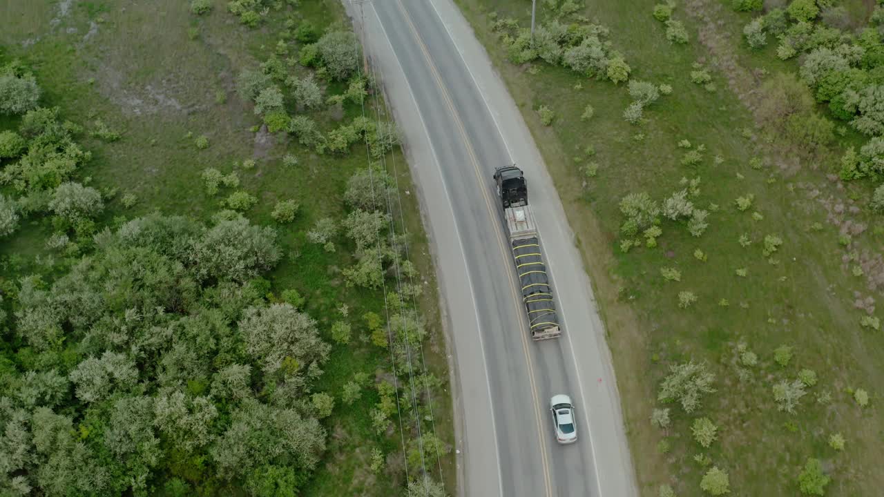 无人机观察卡车行驶在转弯的道路上。俯视图视频素材