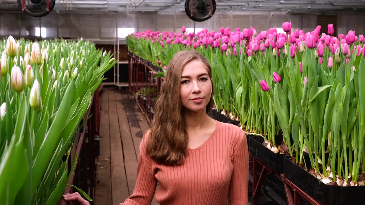 女孩穿着棕色的裙子在郁金香花房里摆姿势视频下载