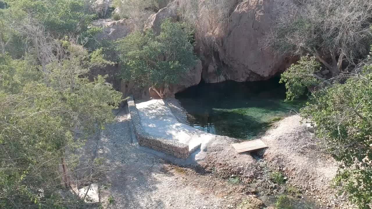 天然水池与一条小河流经岩石沙漠景观视频素材