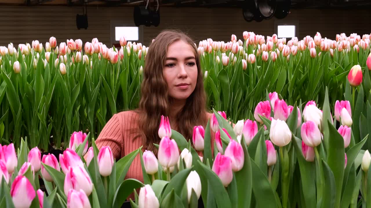 女孩穿着棕色的裙子在郁金香花房里摆姿势视频素材