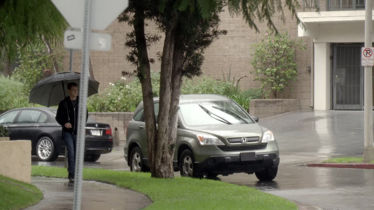 中等角度的行人打着伞在雨中走在人行道上。汽车停在街上。公寓建筑部分可见。视频素材