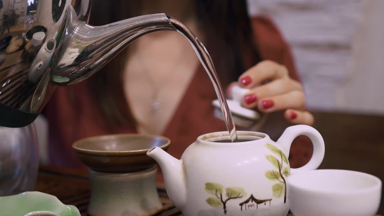 一个女孩把开水倒进茶壶里泡茶，这是一种来自中国的东方传统饮茶方式。茶中含有铈，饮用抗氧化能量饮料视频素材