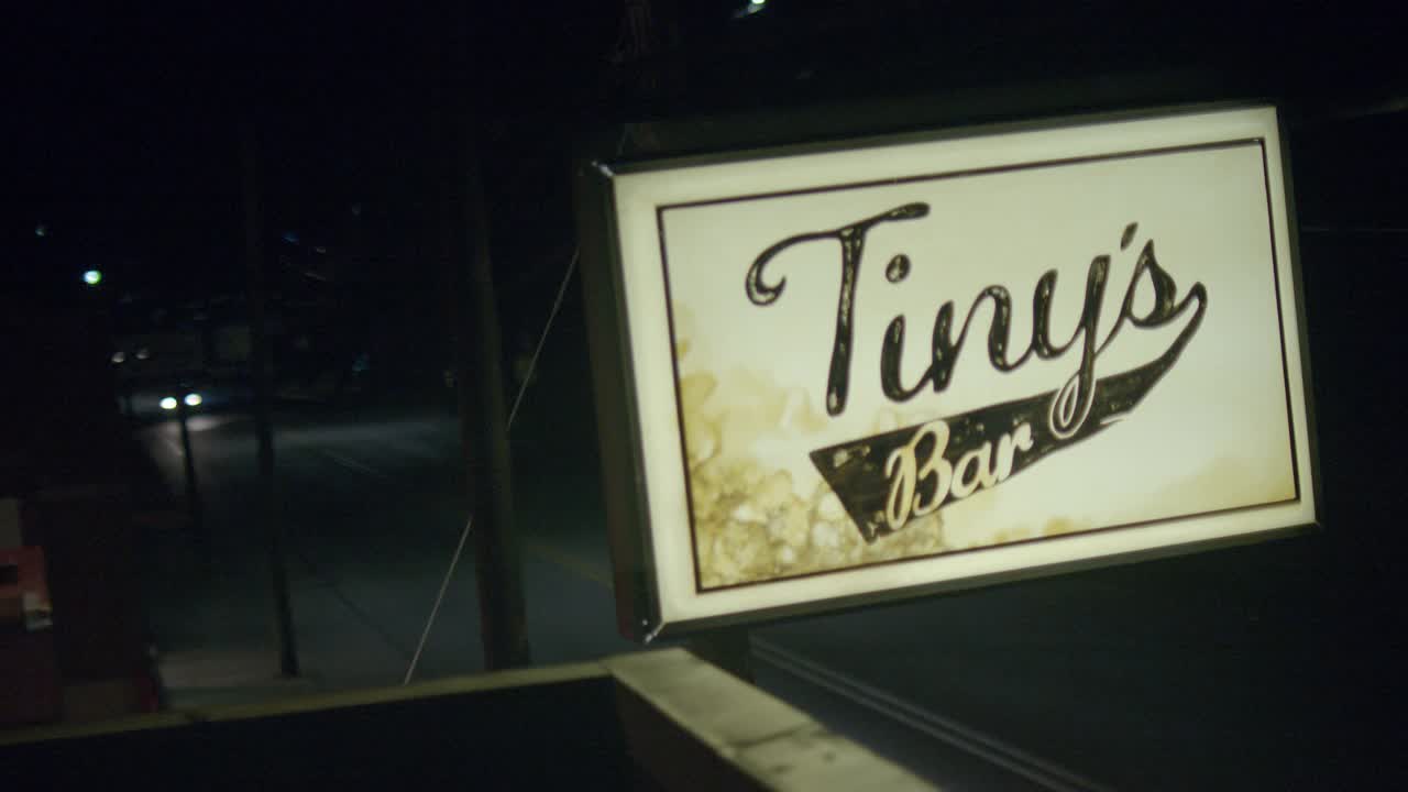 建筑物屋顶“tiny’s bar”标志的闭合角度。在bg的街道上可以看到汽车行驶。视频素材