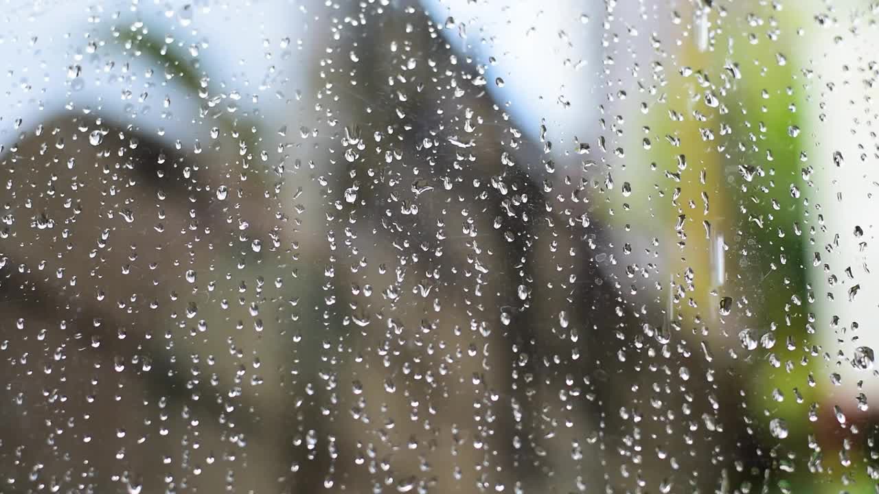 雨落下来，雨落在透明的玻璃上，水慢慢地流过透明的玻璃。视频下载