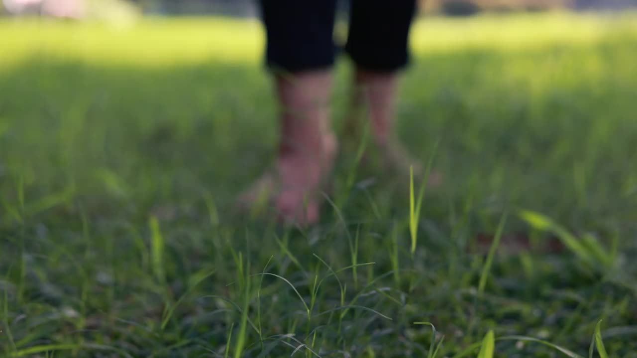 女孩穿着轻盈的夏装，在阳光明媚的户外田野里散步视频下载