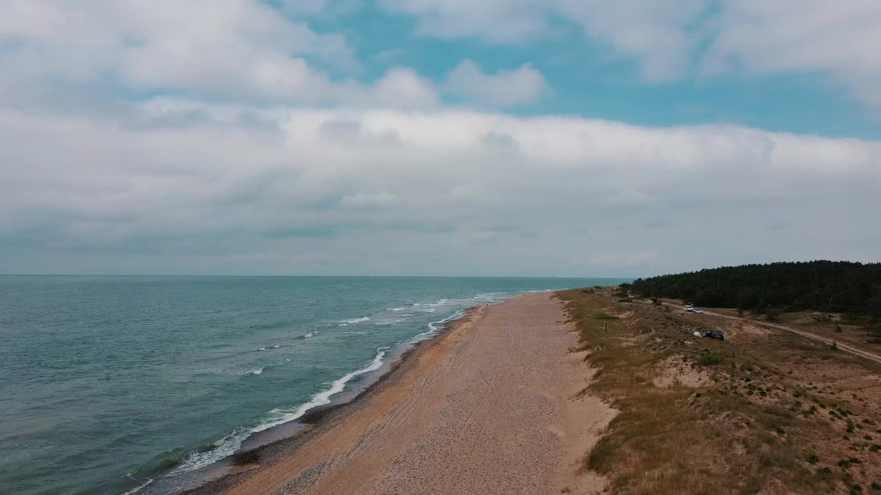 航拍的波罗的海乌扎瓦，拉脱维亚海岸线与海浪从上面的观点。在沙滩上的海浪顶部视图的海浪泡沫和飞溅视频素材