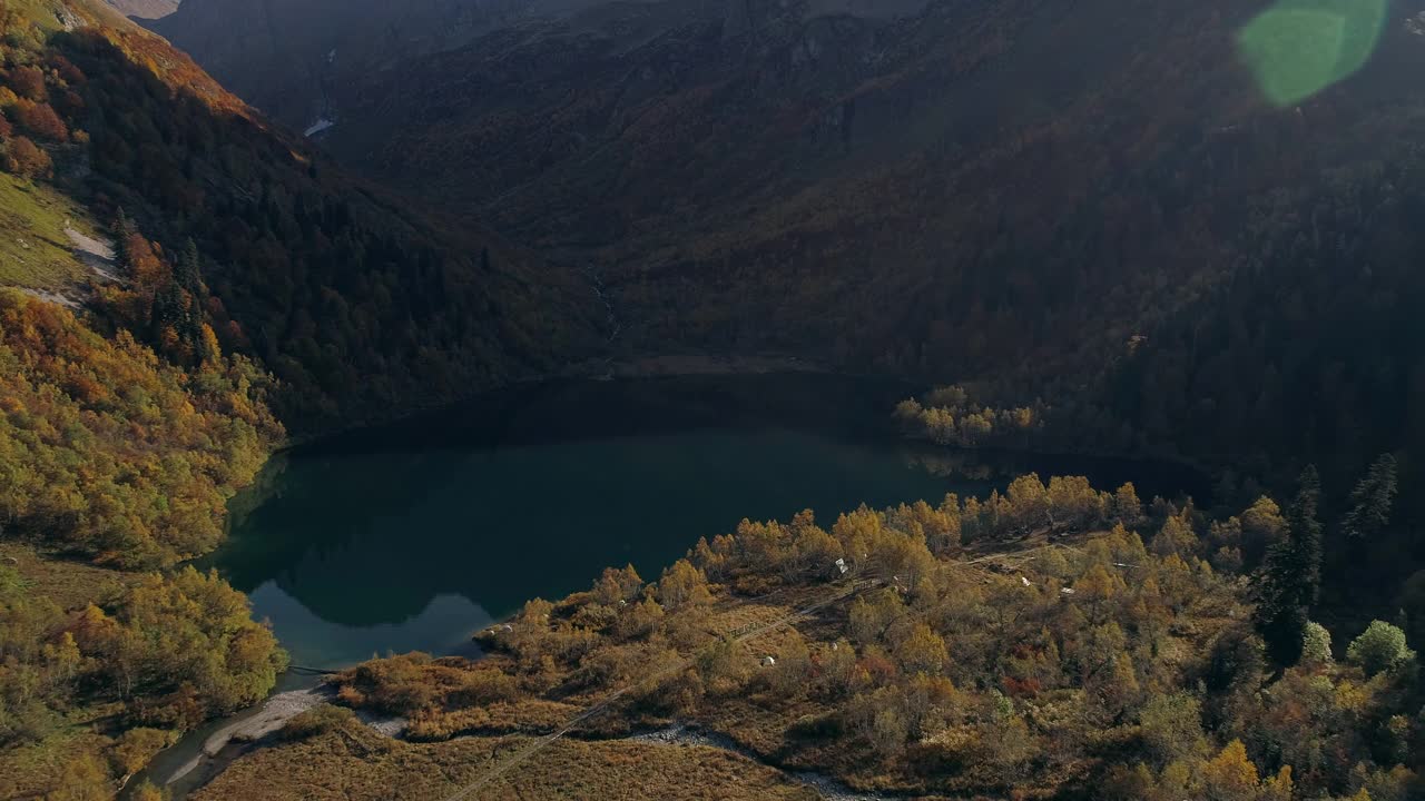 低飞在高山湖泊的岸边。黄色的森林环绕着湖。湖面上山脉、森林和天空的倒影十分清晰。湖面是一面镜子。视频素材