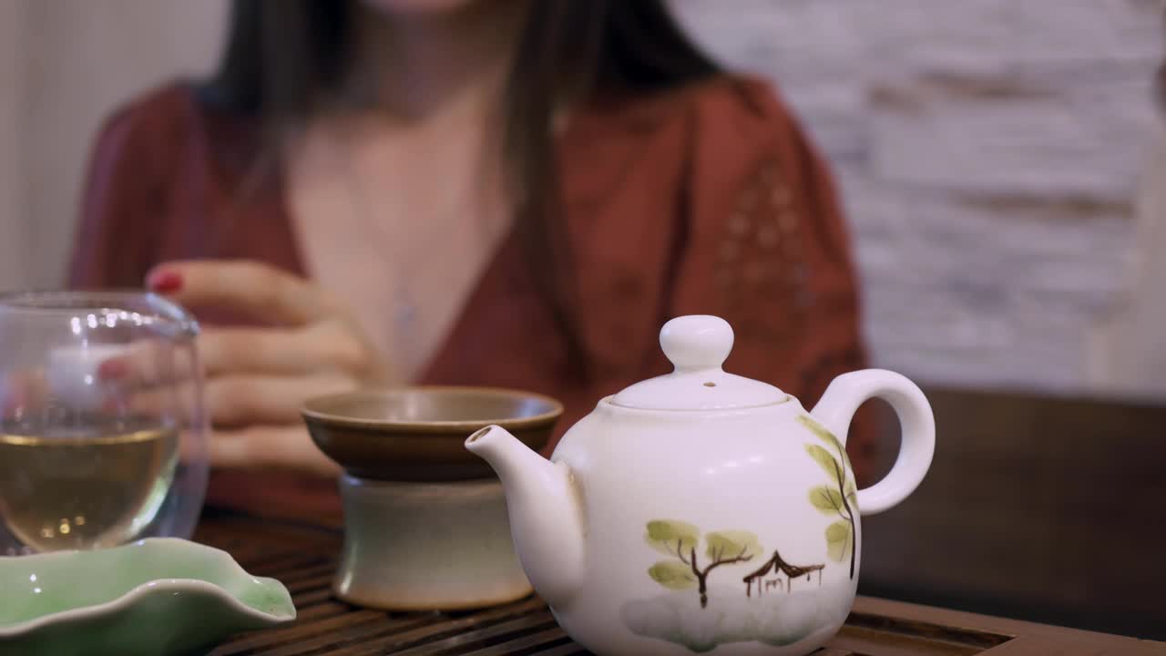 东方饮茶文化。中国饮茶仪式上，桌上有泡茶设备。喝中国乌龙茶或白茶的妇女视频素材