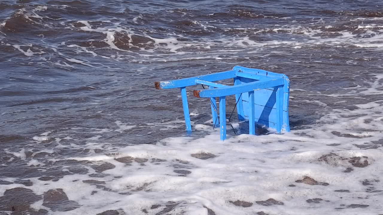 蓝色的木椅随着海浪漂向大海。视频下载