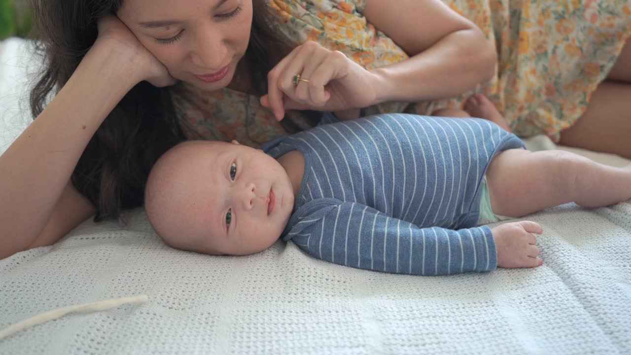 快乐的白种人妈妈和刚出生的小男孩在床上玩耍视频素材