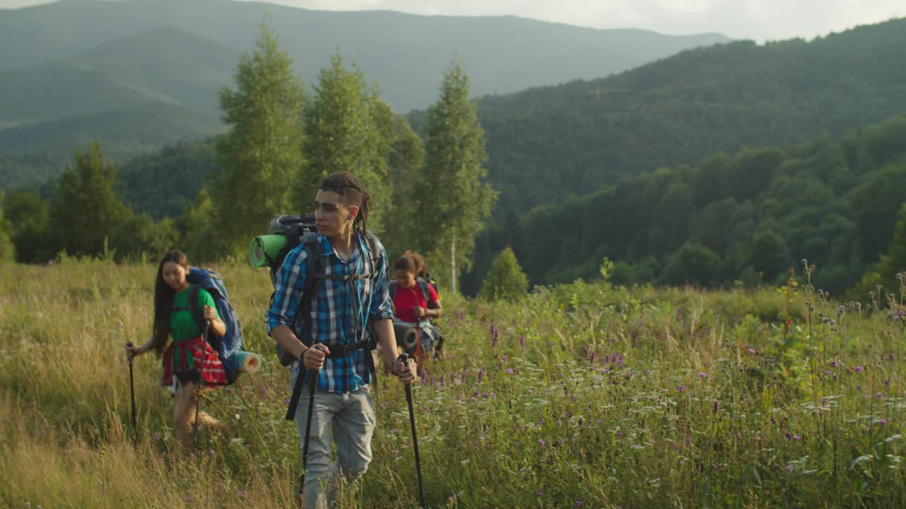 快乐的多元民族背包客，在夕阳下拿着登山杆上山视频素材