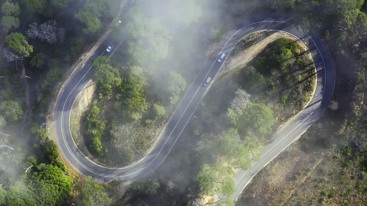 4k无人机拍摄的阴天，汽车行驶在林地的道路上视频素材