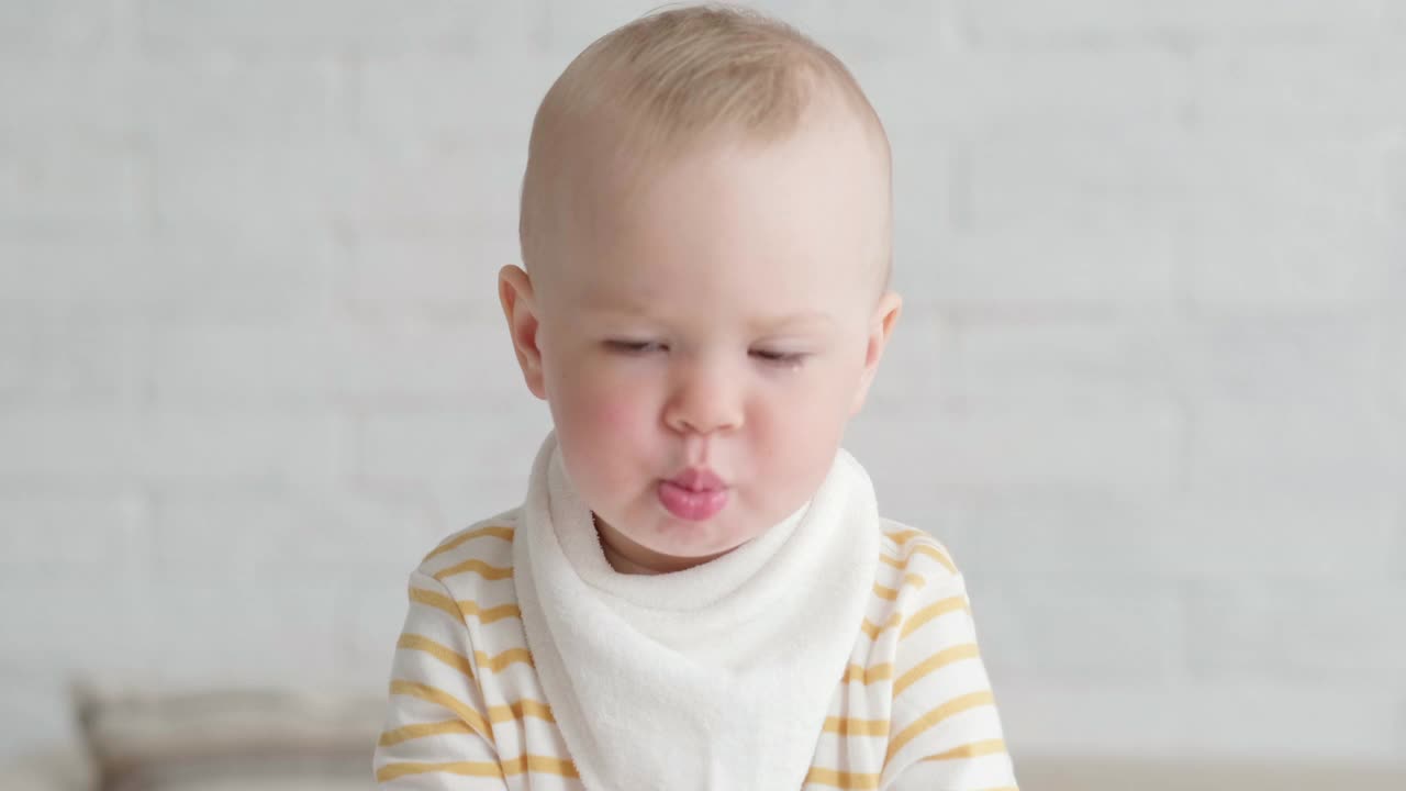 在家吃宝宝的照片。健康食品，午餐时间。孩子做鬼脸。孩子坐在桌子上，手里拿着碗视频素材