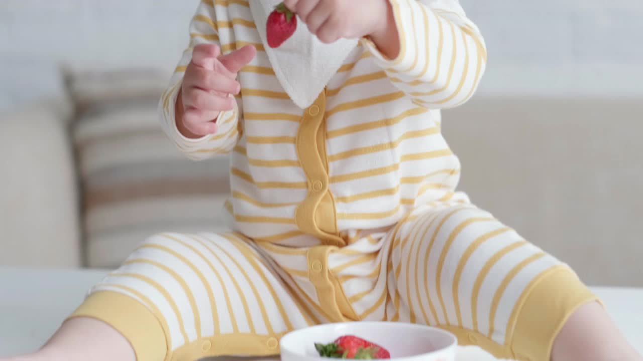 在家吃宝宝的照片。健康食品，午餐时间。孩子做鬼脸，把红草莓放进嘴里视频素材