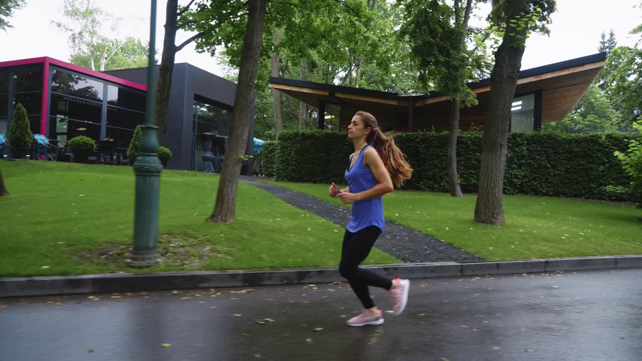 一个健康的女人雨后在公园慢跑视频素材