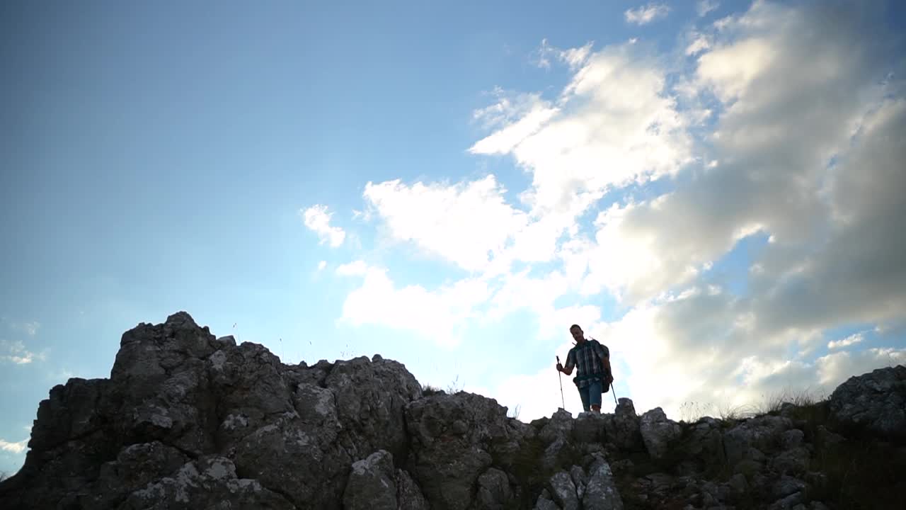 前面的幸福人像爬上了悬崖峭壁的边缘。游客徒步旅行登山旅行用登山杆视频素材