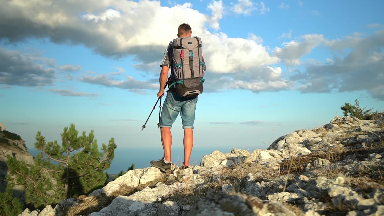 旅行，登山，徒步旅行的年轻人的观点，徒步旅行者的欢乐和站在海边的岩石在夏天SPBD视频素材