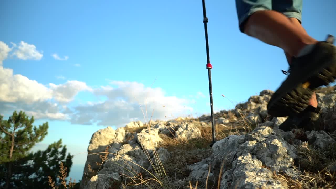 男人爬上悬崖边，看着天空。背包客徒步旅行登山旅行的岩石与徒步旅行视频素材