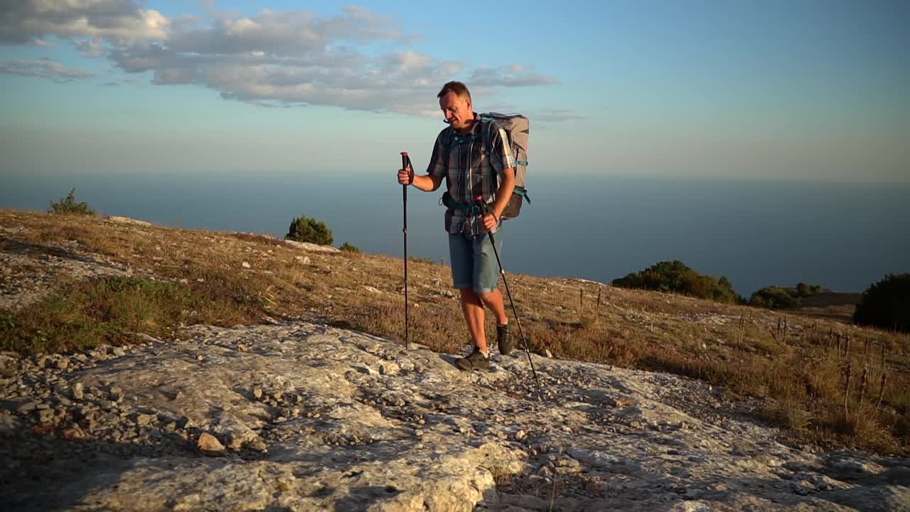 年轻的男性徒步旅行者在令人惊叹的自然景观的背景下登山视频素材