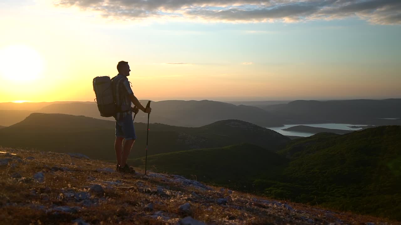 攀登者剪影登山徒步旅行享受金色夕阳，站在阳光Spbd。男人背着背包徒步旅行视频素材