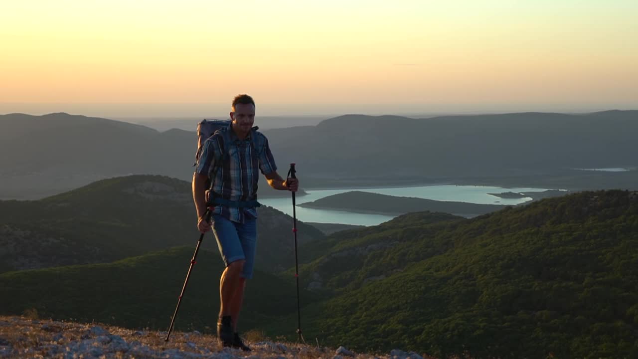 兴奋的男徒步者，徒步登山，享受日落。男人旅行者用徒步攀登岩石视频素材