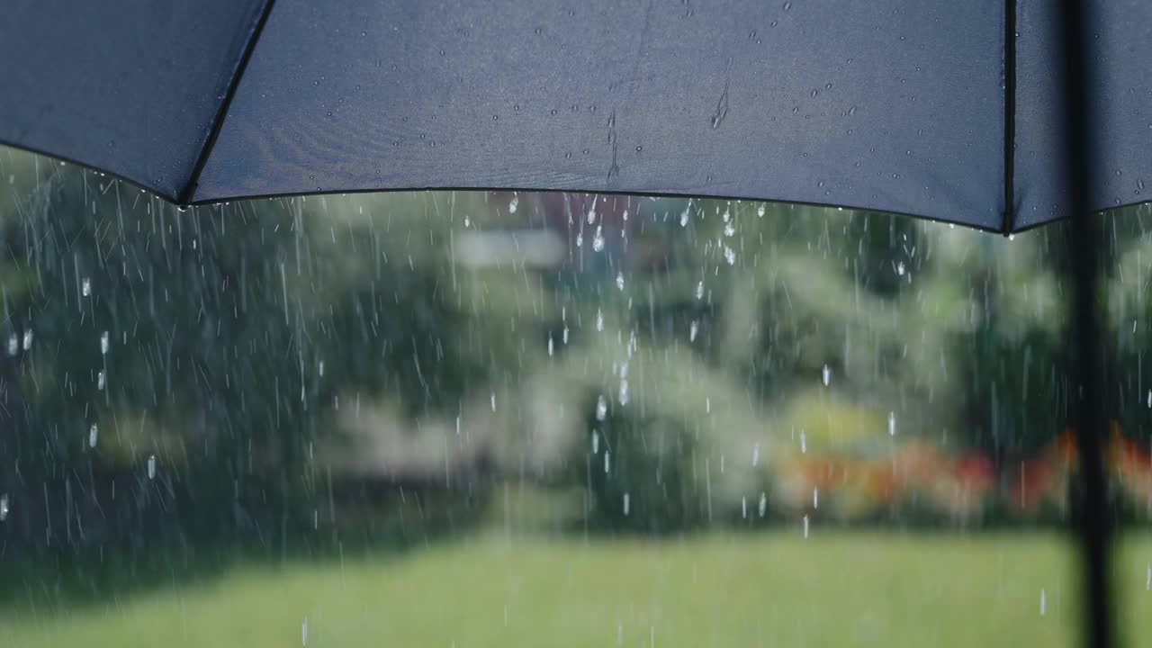 阳光明媚的夏雨。水珠从灰色的伞面上流下来视频素材