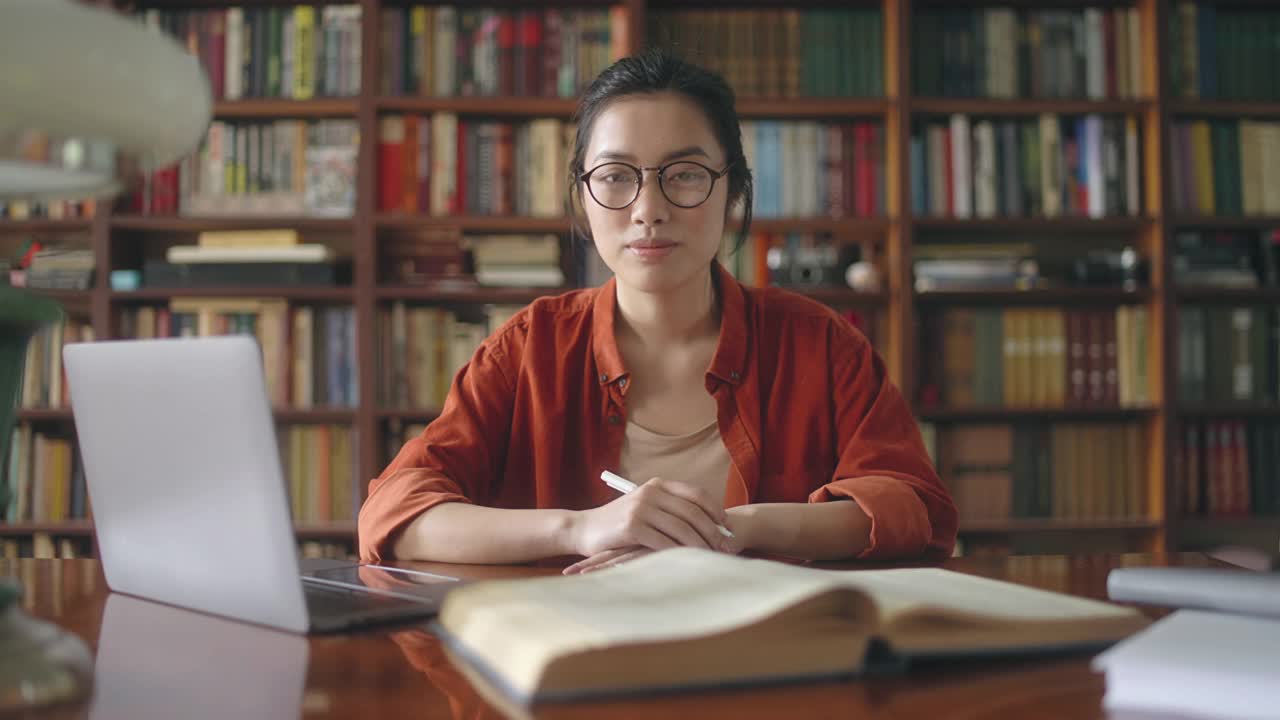 微笑的亚洲女学生肖像花时间在图书馆学习视频素材