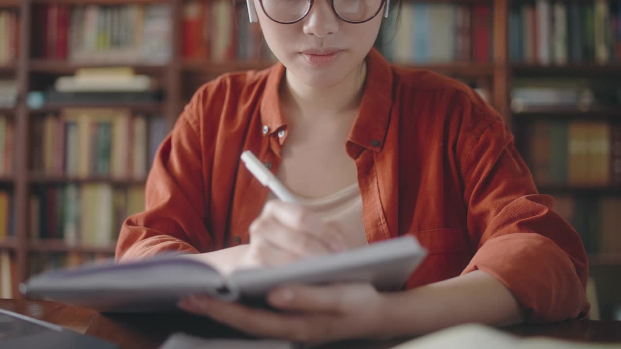 勤奋的亚洲学生在网上上课，做笔记，坐在图书馆视频素材