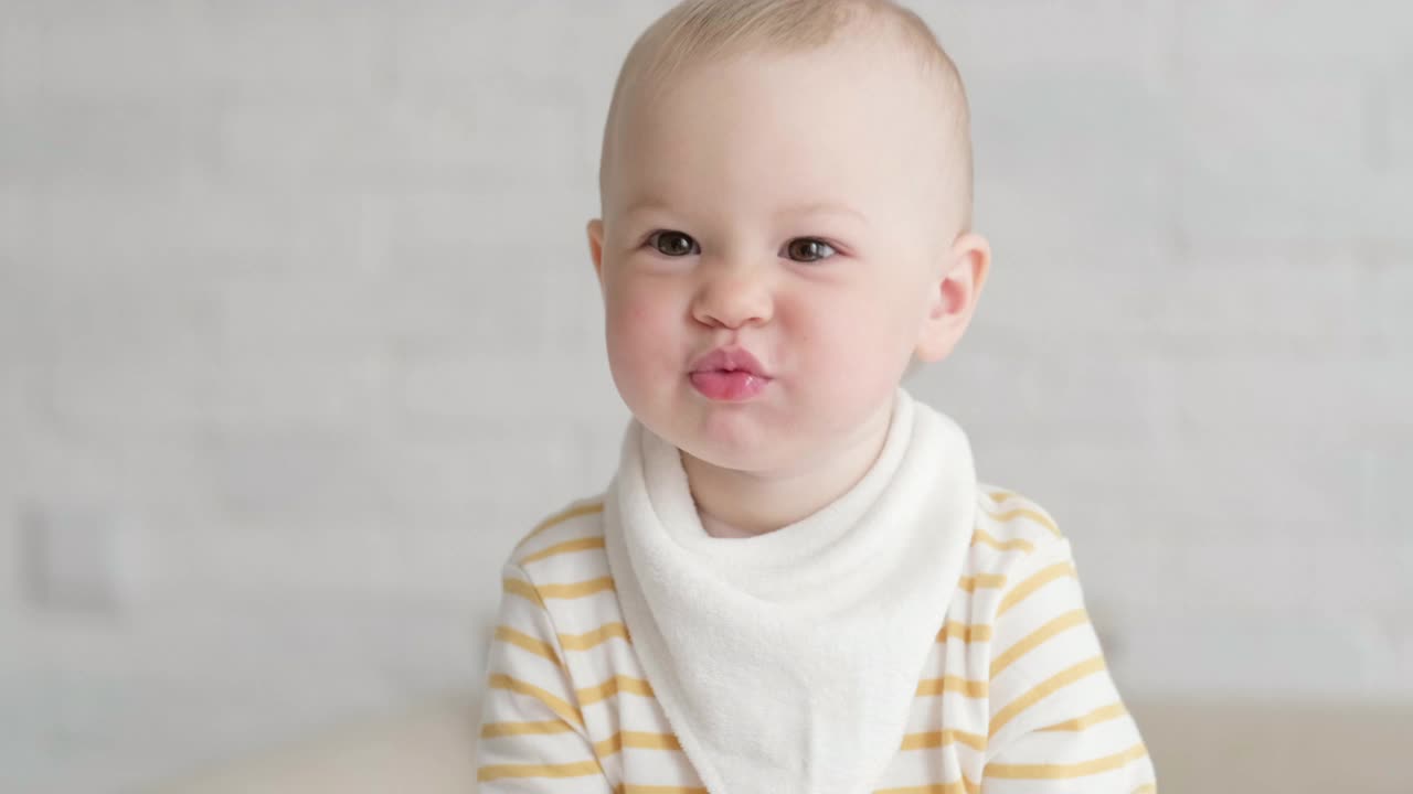 在家吃宝宝的照片。健康食品，午餐时间。孩子做鬼脸。孩子坐在桌子上，手里拿着碗视频素材