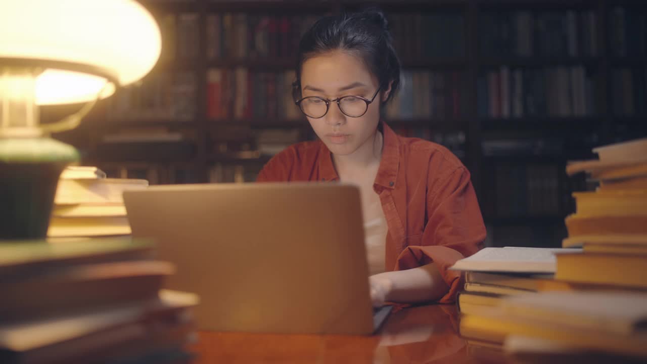 亚洲女性自由职业者，在城市图书馆工作到深夜，做研究视频素材