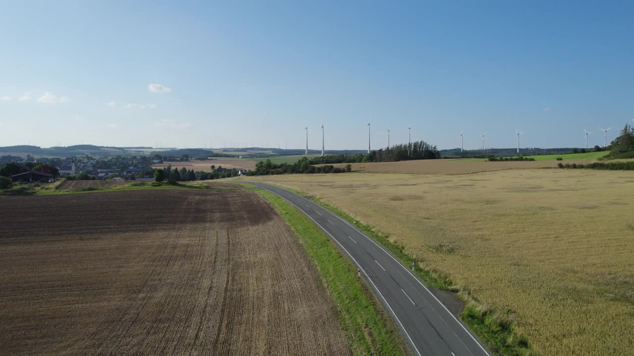 乡村风景中的乡村道路，地平线上有风力涡轮机(空中)视频素材