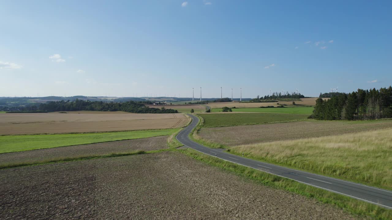 乡村风景中的乡村道路，地平线上有风力涡轮机(空中)视频素材