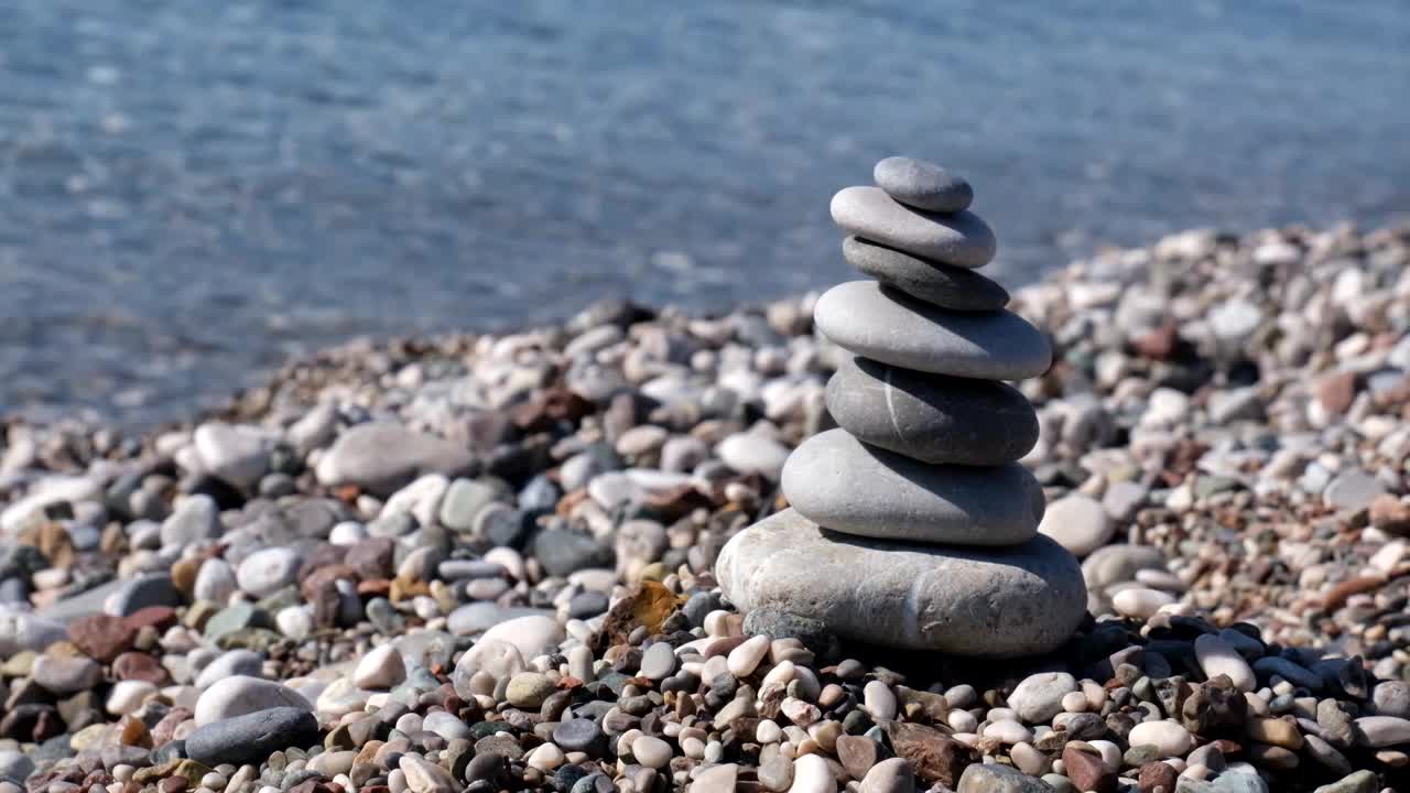 沙滩上的石塔和海浪的背景，卵石金字塔，视频下载