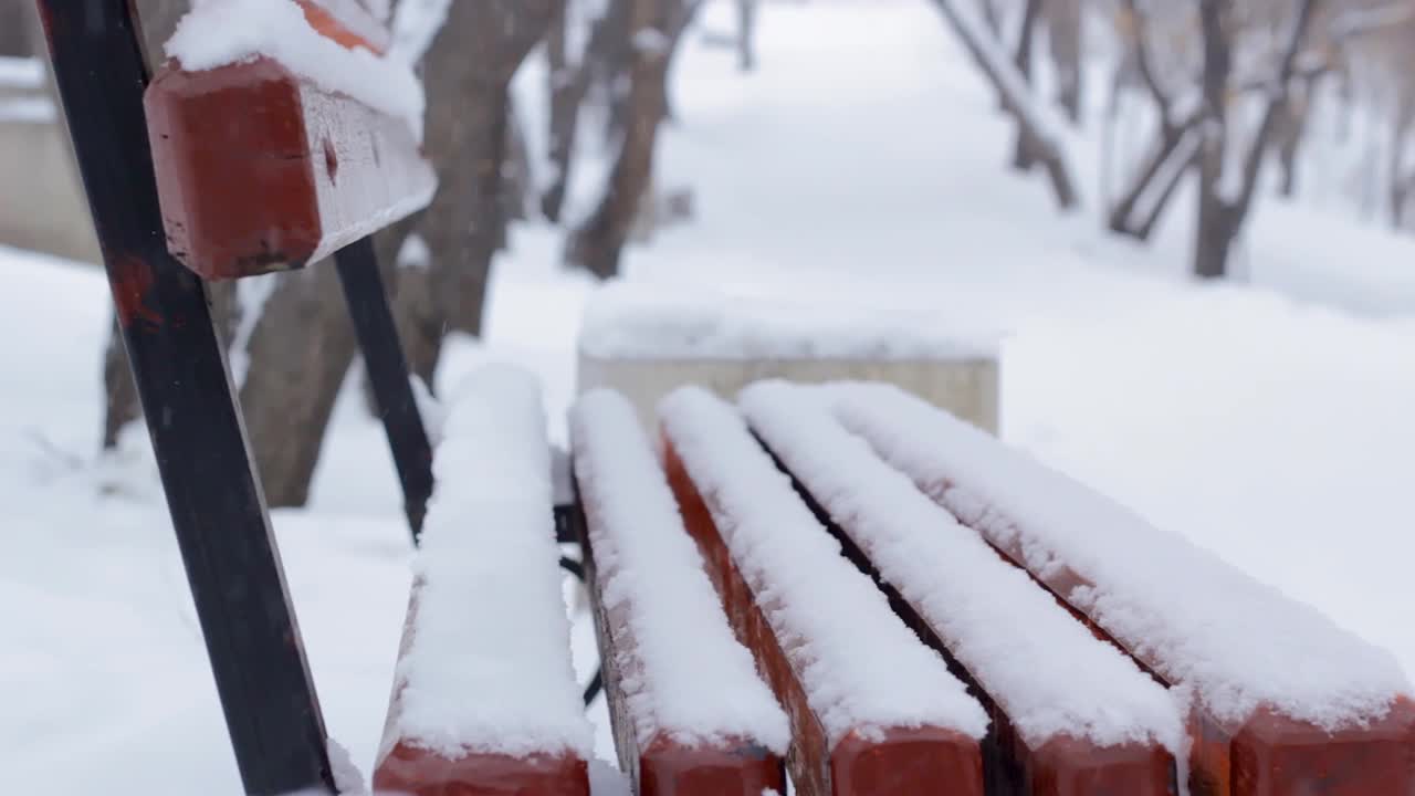 冬天的公园里下雪了，下雪的季节里，巷子里的人行道上积满了雪，积雪下空荡荡的长凳视频素材