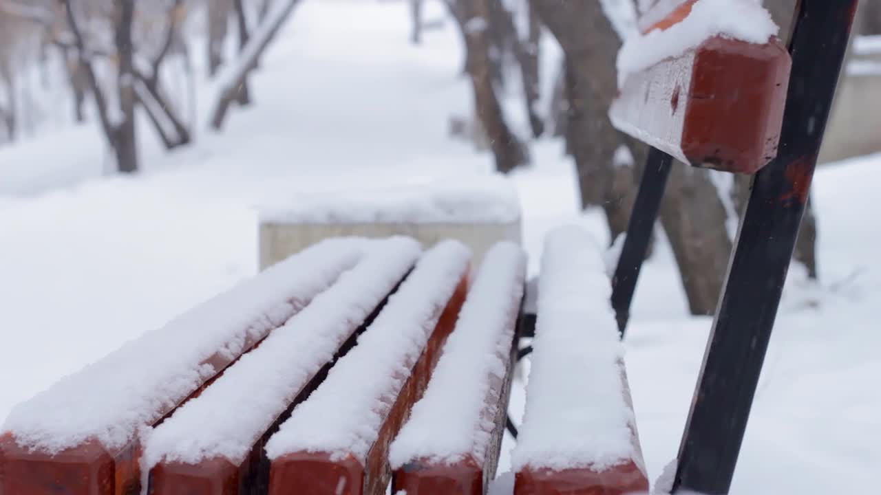 冬天的公园里下雪了，下雪的季节里，巷子里的人行道上积满了雪，积雪下空荡荡的长凳视频素材