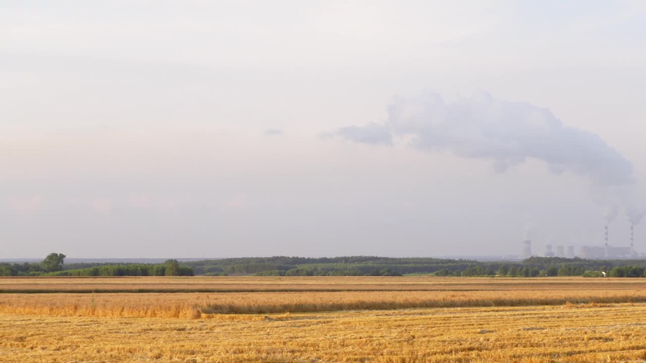 背景是一个大型燃煤电厂的农田全景。视频素材