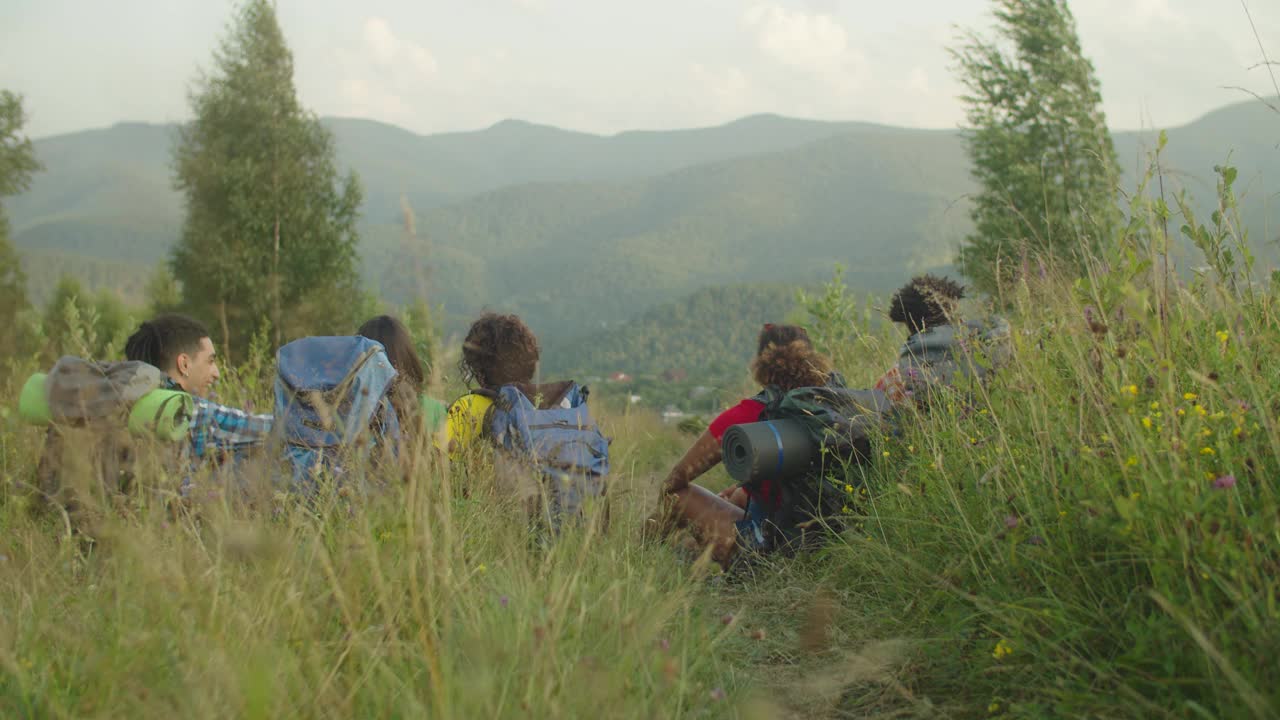 在山顶欣赏山景的多民族徒步旅行者视频素材