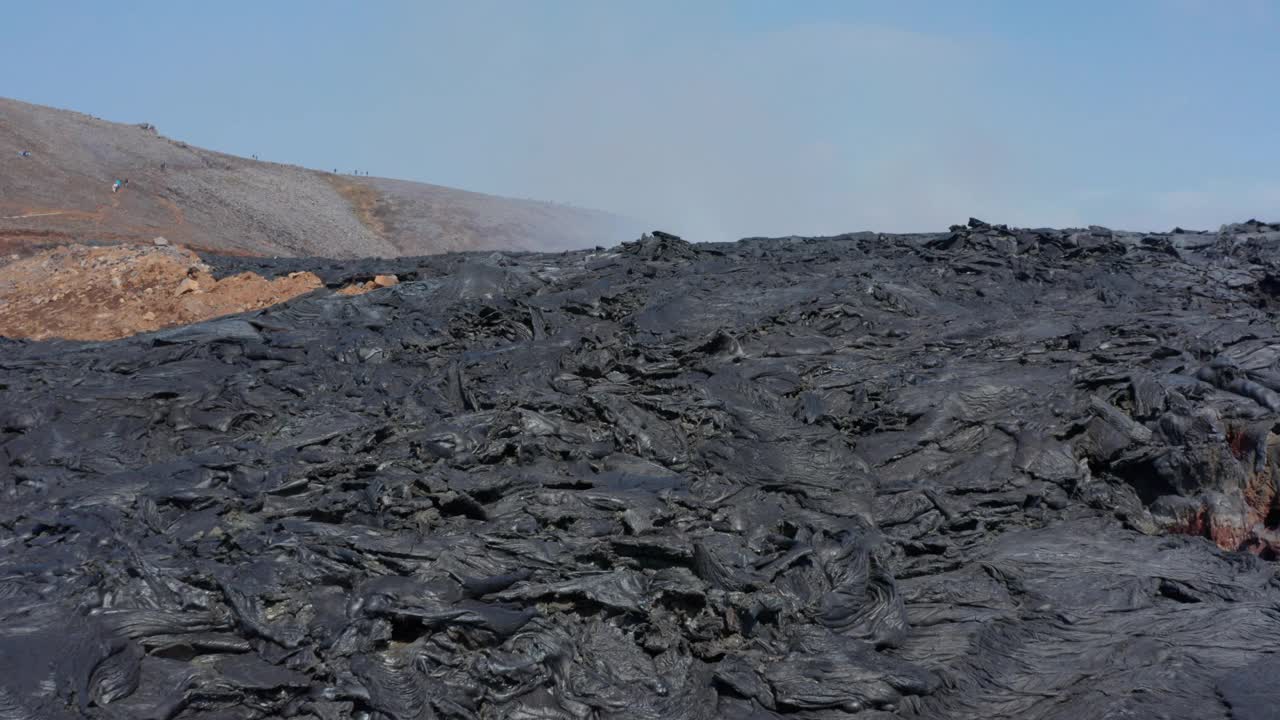 冰岛Fagradalsfjall超凡脱俗的火山景观。无人机在黑色烟雾熔岩上方低空飞行，推车进入，白天视频素材