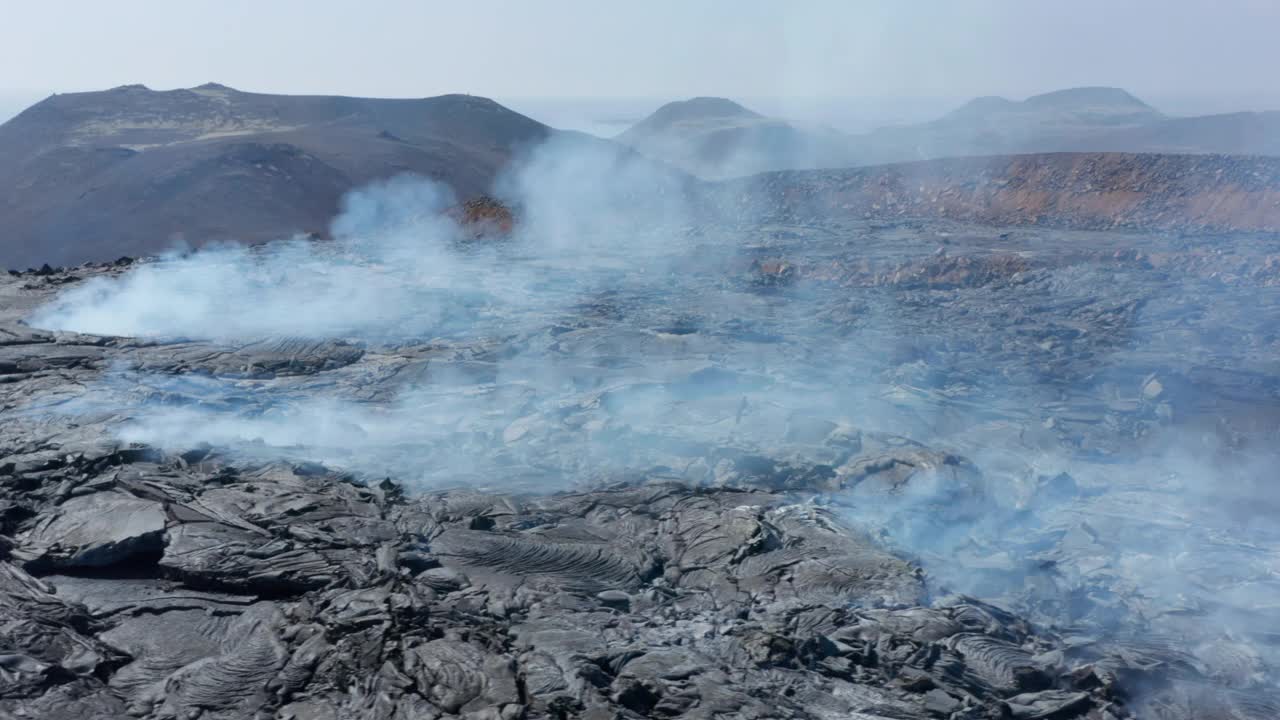 空中无人驾驶飞机在黑色烟雾熔岩坑周围盘旋，游客们正在远处的fagradalsjall火山观光视频素材