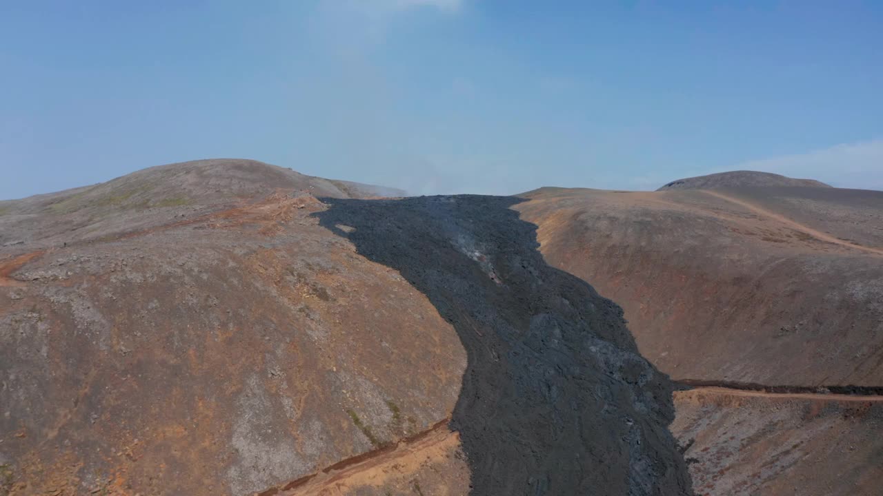 超凡脱俗的冰岛fagradalsjall景观。无人机向前飞向黑色熔岩河流动之间的山脉，无人机低附近烟雾熔岩，一天视频素材