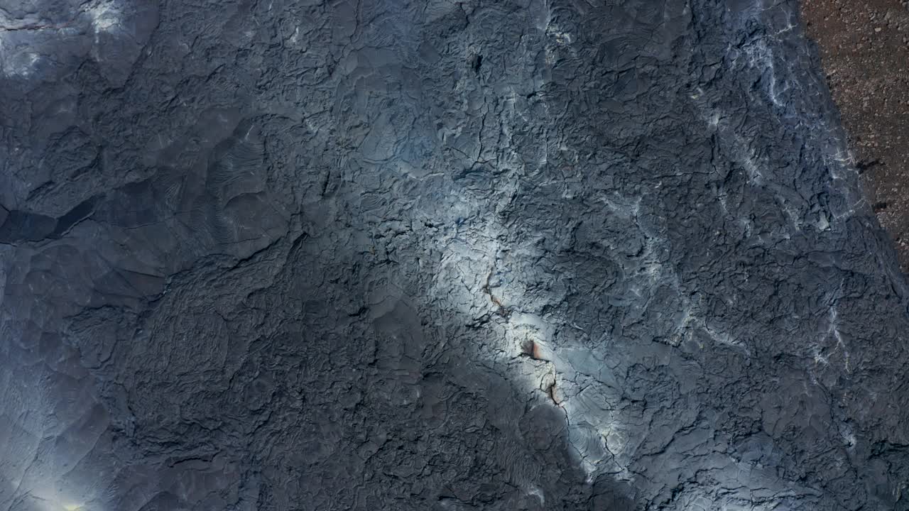 盘旋而下的鸟瞰头顶上的黑灰色的熔岩裂缝，法格拉达斯火山，冰岛，天视频素材