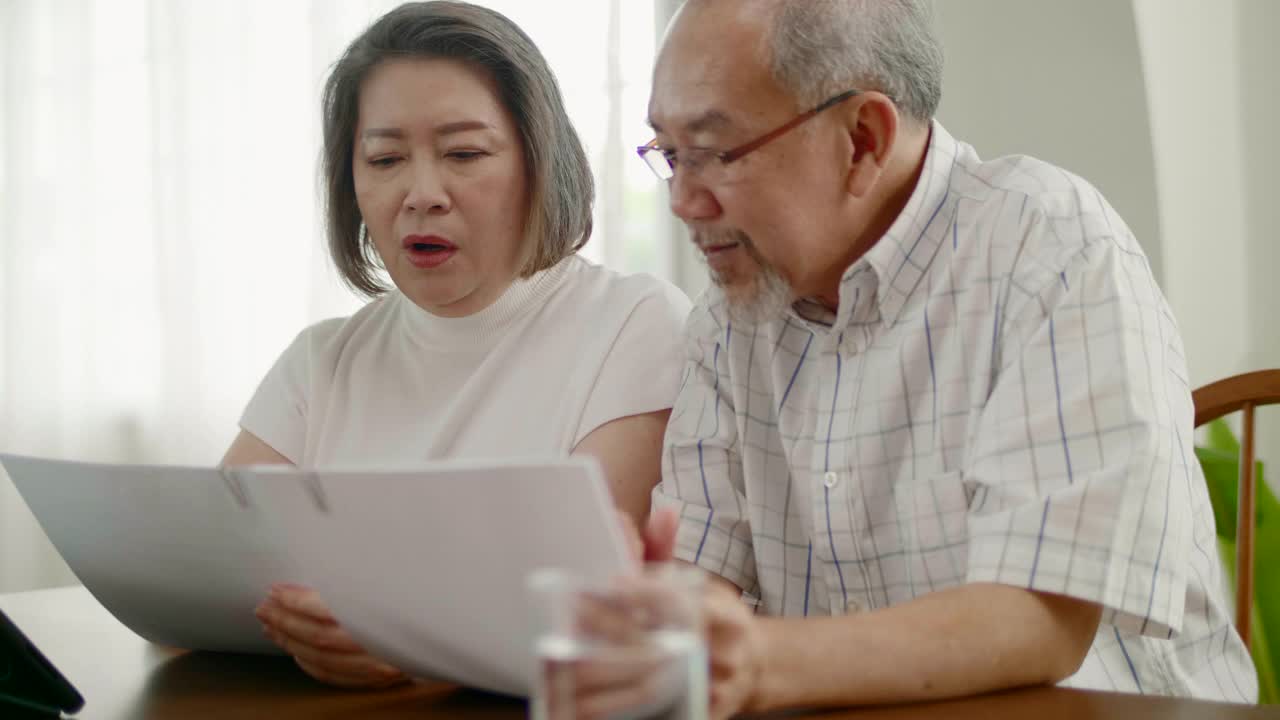 老年夫妇使用数字平板电脑技术管理家庭预算视频素材