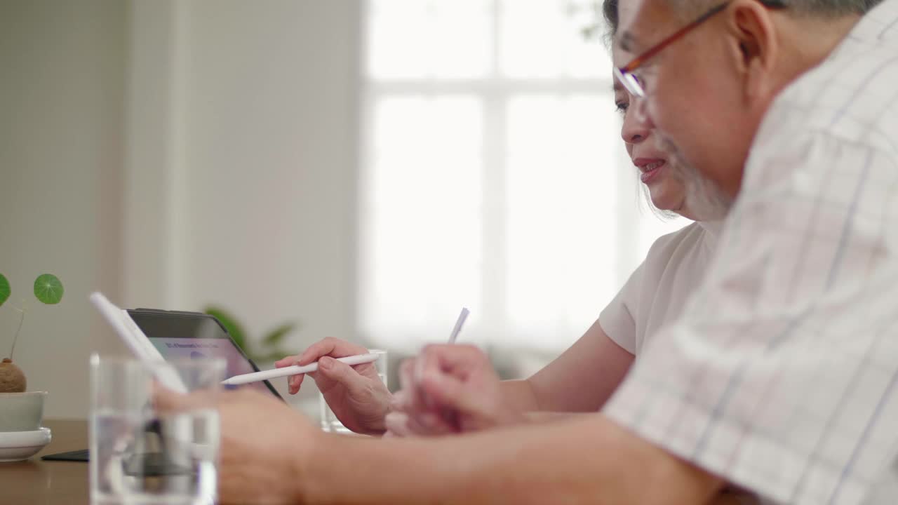 老年夫妇使用数字平板电脑技术管理家庭预算视频素材