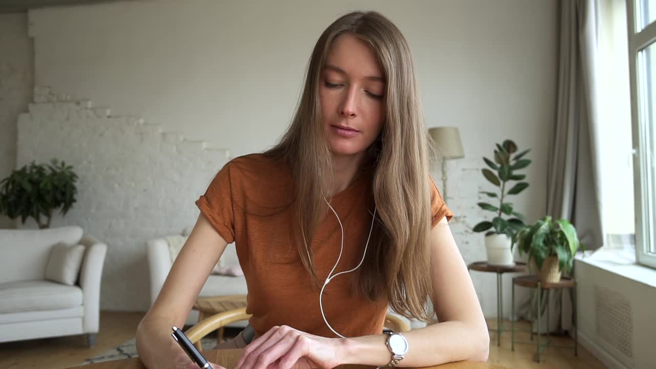 女人在笔记本上写笔记，通过视频通话，肖像网络摄像头视图。女性虚拟研究视频素材