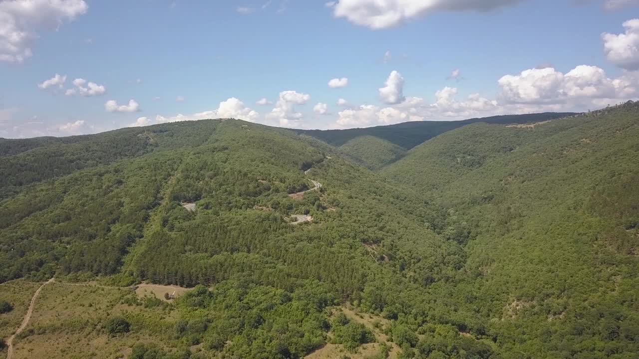 鸟瞰图的蜿蜒的道路与割草汽车和卡车在高山口，槽茂密的树林。视频素材